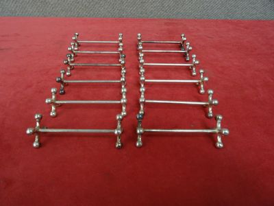 un lot de six porte-serviettes chromés posés sur un tapis rouge