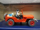 une jeep miniature conduite par un homme sur un fond bleu