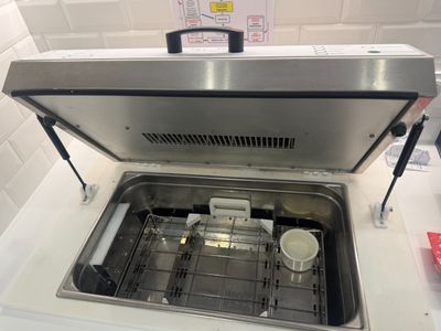 an open dishwasher sitting on a counter in a kitchen