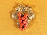 a brooch with red berries on it on a yellow cloth