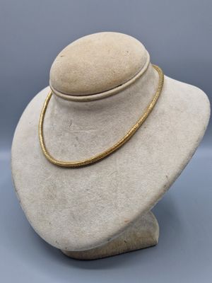 a close up of a white mannequin with a gold necklace on it