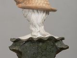statue of a man with a hat on top of a green and white vase