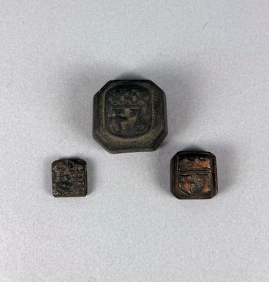 three small metal objects sitting on top of a white surface