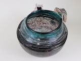 a glass jar with a small bird on it