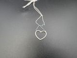 a close up of a silver necklace with a heart hanging from it