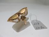 une photo d'une bague papillon en or à laquelle est accrochée une étiquette