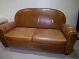 un canapé en cuir marron posé sur un sol recouvert de moquette
