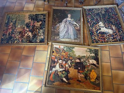 de nombreux tableaux accrochés au mur d'une pièce dotée d'une cheminée
