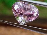 un diamant rose en forme de cœur tenu par une pince