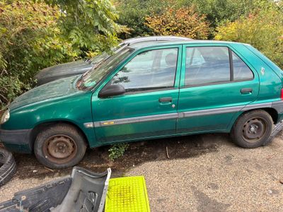 une voiture verte garée à côté d'un tas de ferraille