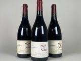 trois bouteilles de vin sont alignées sur une table