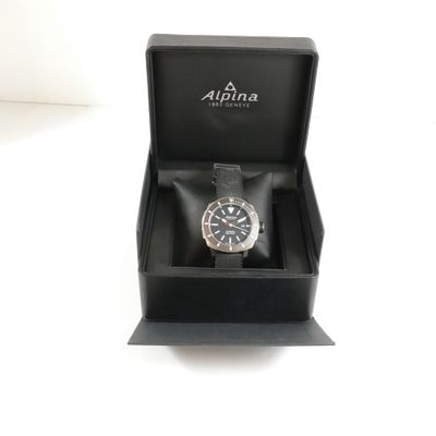 une montre dans une boîte noire posée sur une surface blanche