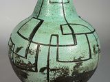 un vase vert orné de motifs noirs et blancs