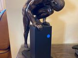 une statue représentant un homme penché au-dessus d'une boîte