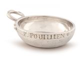 a small silver bowl with a handle on a white surface
