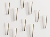 des appliques murales blanches et dorées sur un mur blanc