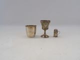deux tasses en argent et une tasse en argent posées sur une surface blanche