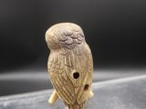 a close up of an owl figurine on a clear surface