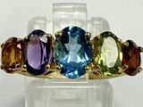 une photo en gros plan d'une bague ornée de trois pierres de couleurs différentes