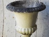 a stone urn sitting on a stand on a wooden floor