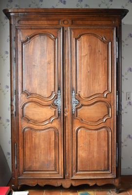 une armoire en bois dans une pièce dont le mur est recouvert de papier peint