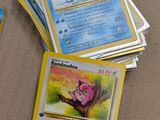 several pokemon cards are sitting on a table next to a cell phone