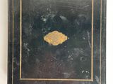 an old black and gold box with a gold leaf on it