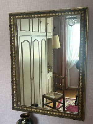 un miroir accroché au mur au-dessus d'une chaise dans une pièce