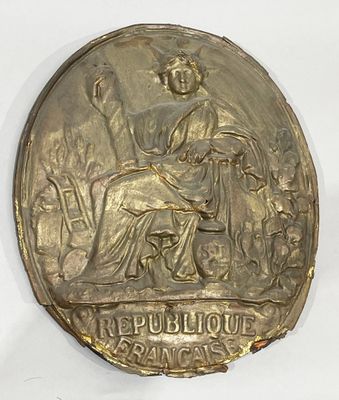 gold medal with a woman seated on a bench in a garden