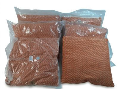 trois sacs remplis d'oreillers marron posés sur une surface blanche