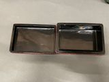 pair of black and red trays with lids on a table