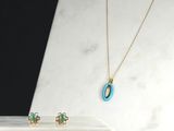 Ensemble collier et boucles d'oreilles turquoise et or posé sur une plaque de marbre