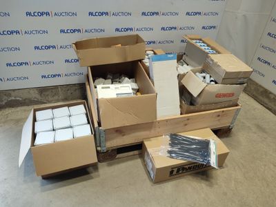 Plusieurs cartons contenant des objets divers sont posés par terre devant un mur.