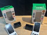three cell phones are sitting on a table next to a box of live life