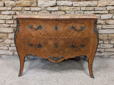 an antique chest of drawers with marble top in front of a stone wall