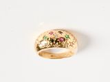 un gros plan d'une bague en or sertie de pierres roses et vertes
