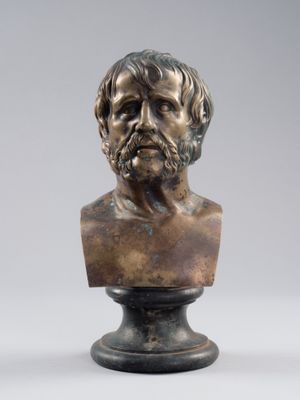 un buste en bronze représentant un homme barbu, posé sur un socle
