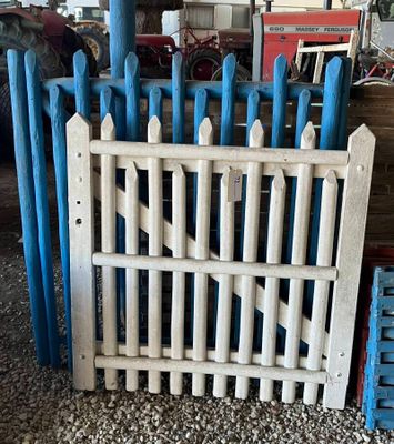 une clôture blanche avec des poteaux bleus devant un mur de briques