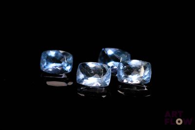 three pieces of blue topazte on a black surface