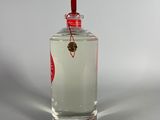 a small glass bottle with a red lid on a white surface