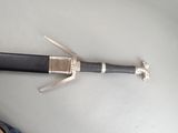a sword that is laying on the floor next to a person ' s feet
