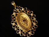 a close up of a gold pendant on a black surface