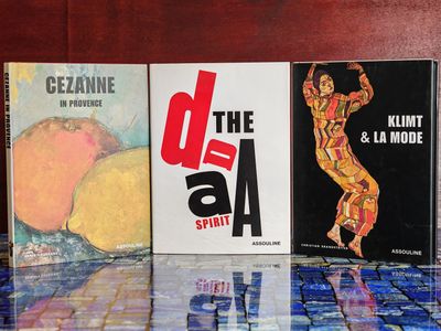 Plusieurs livres sont alignés sur une table devant un mur en bois.