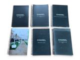 four chanel notebooks are lined up on a white surface