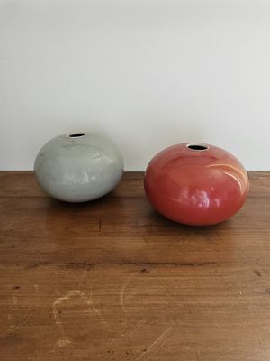 deux vases posés sur une table en bois, avec un mur blanc en arrière-plan