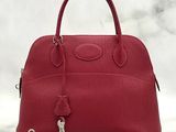 a red leather handbag with a lock on top of it