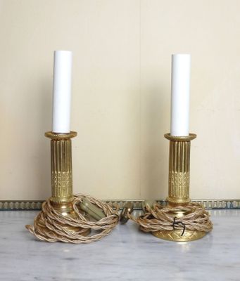 une paire de bougeoirs en laiton entourés d'une corde, posés sur une table en marbre