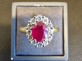 une image d'une bague avec une pierre rouge entourée de diamants blancs
