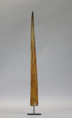wooden sculpture of a long horn on a stand against a white background