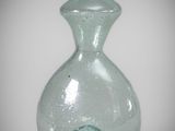 a green glass vase with a small wave inside of it